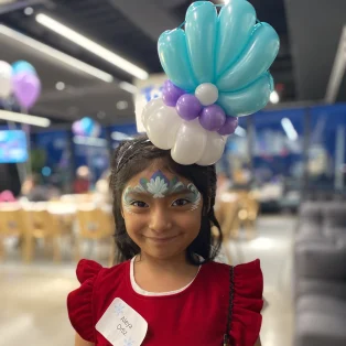 Aleya Ortiz wearing a blue and white balloon crown and detailed face paint at a party