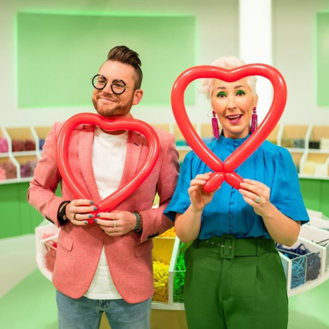 Dave Brenn and a partner posing with red balloon hearts during a colorful and fun balloon crafting session.