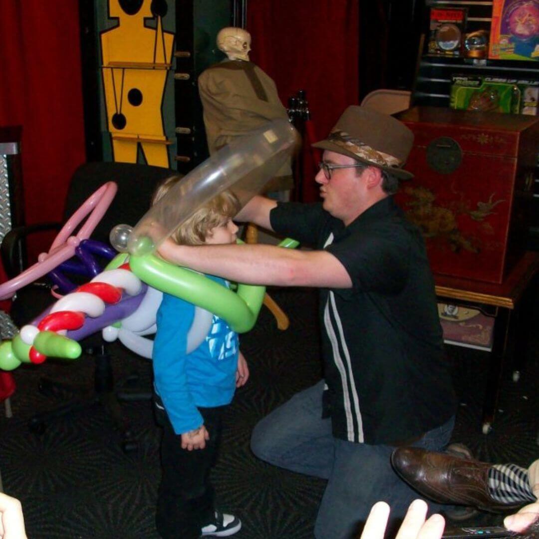 Dave Brenn fitting balloon jetpack on child during magic show