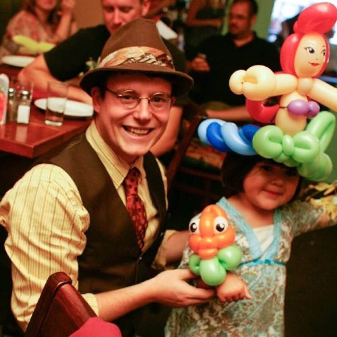 Dave Brenn with child wearing mermaid balloon hat and turtle balloon