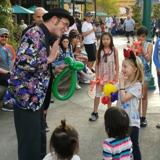 Dave Brenn performing balloon sculpting for children outdoors at an event