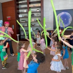 Dave Brenn leading children in a balloon wand dance activity at a birthday party